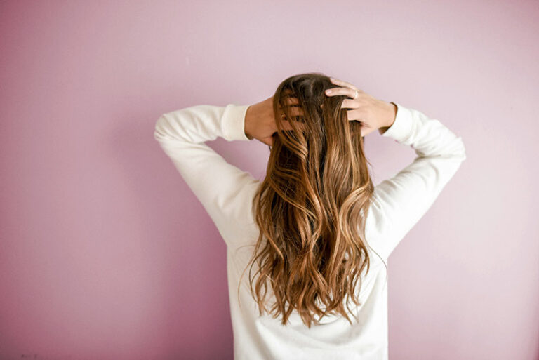 photo of woman in white holding her hair