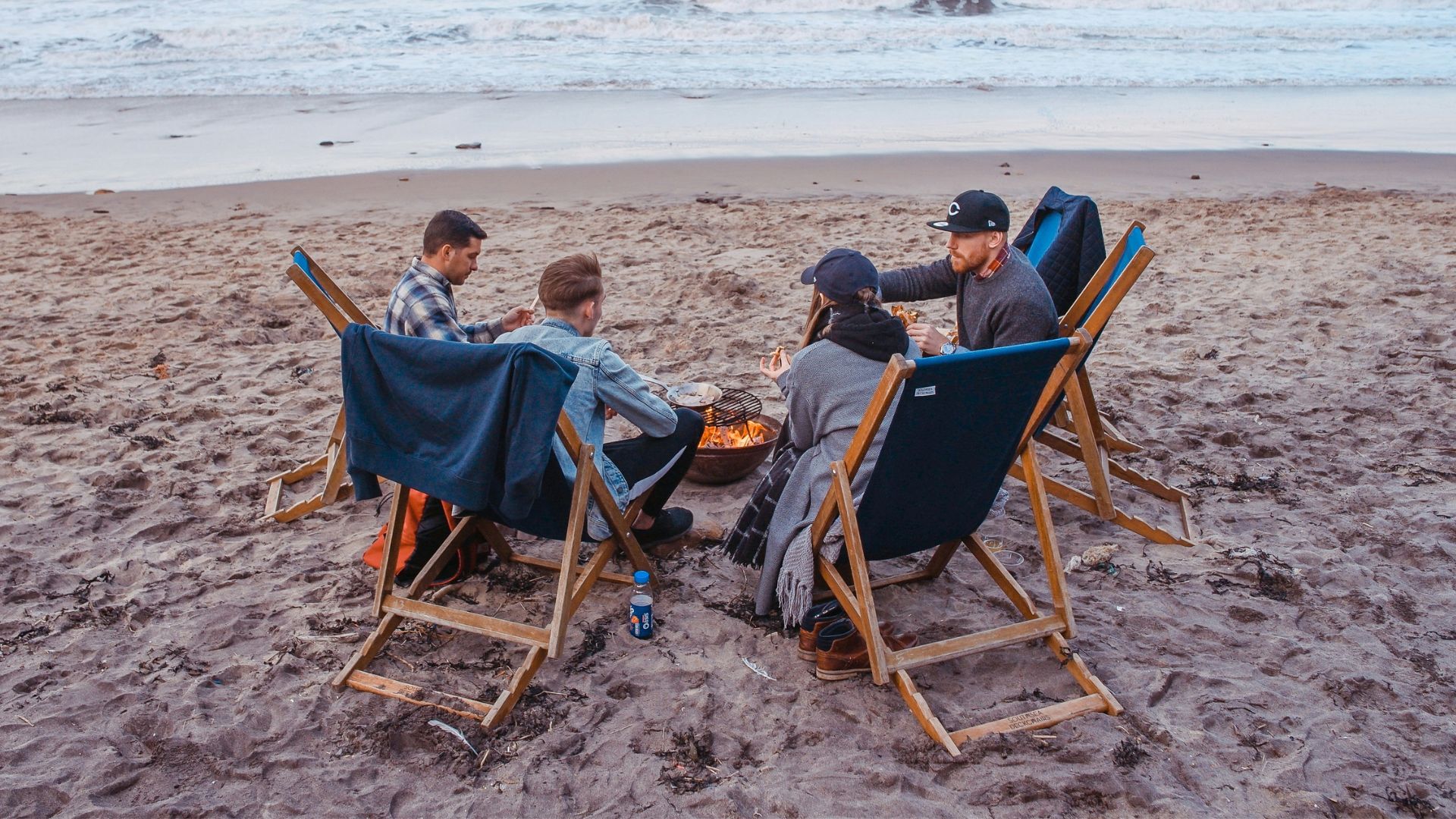 three men and one woman sitting on beach lounge