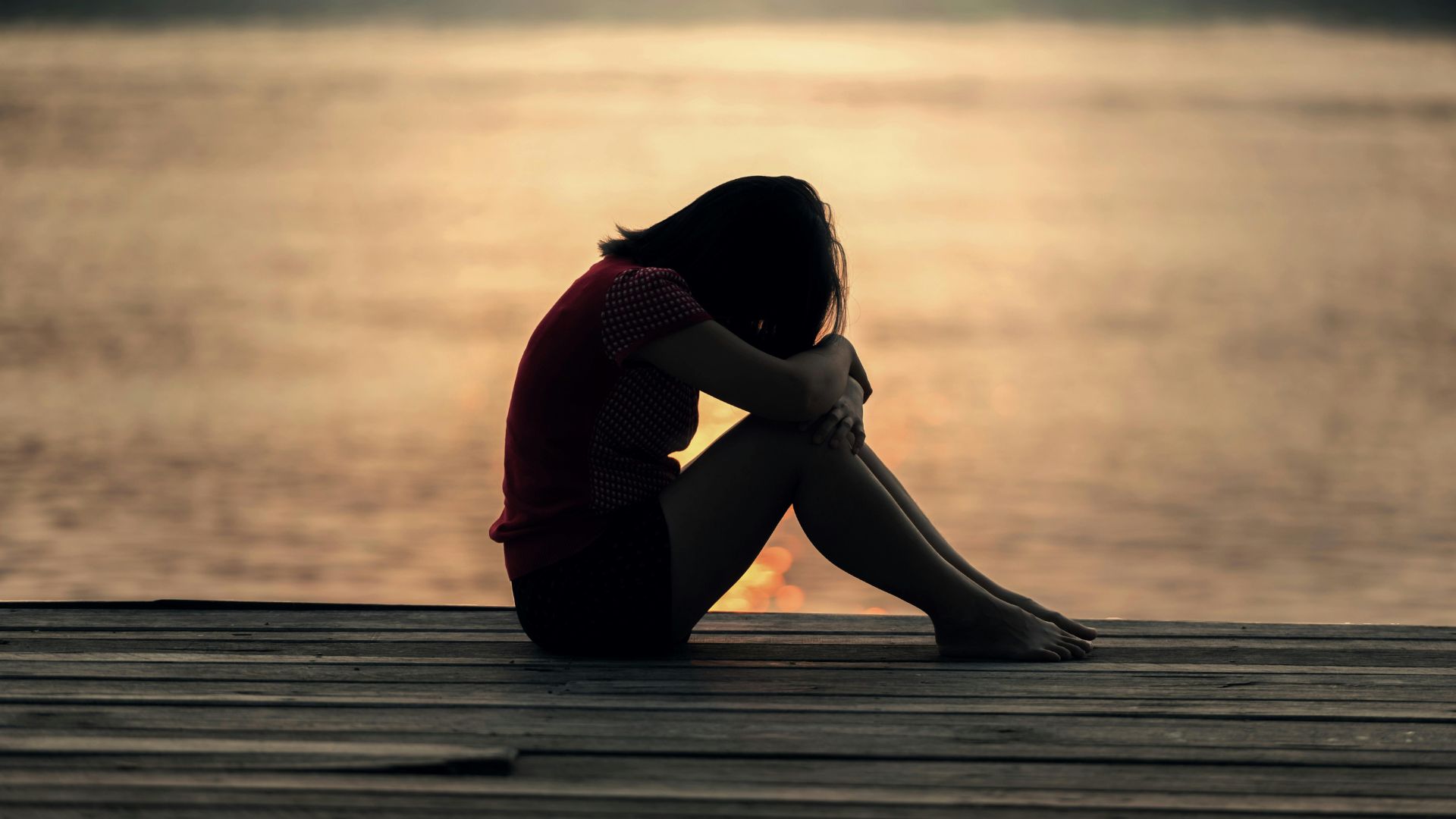 woman looking at sea while sitting on beach