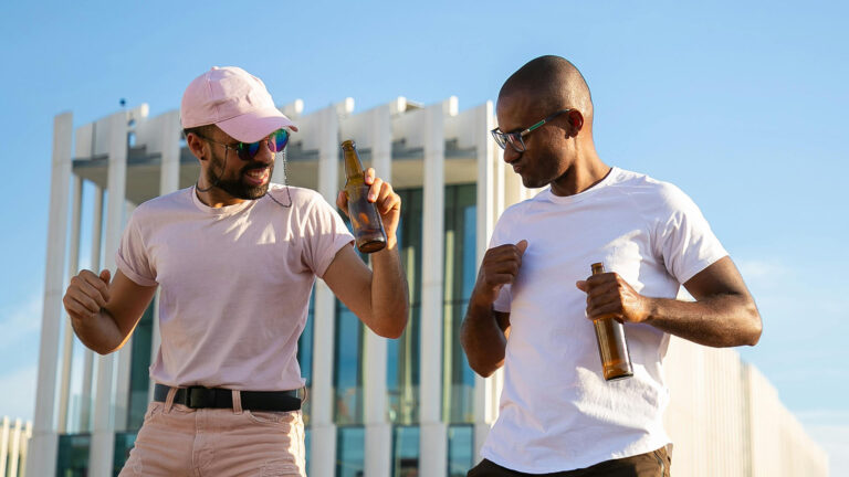 cheerful diverse men having drinks and chatting on rooftop