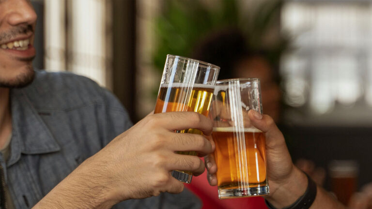 A Man Holding a Drinking Glass with Beer while Toasting