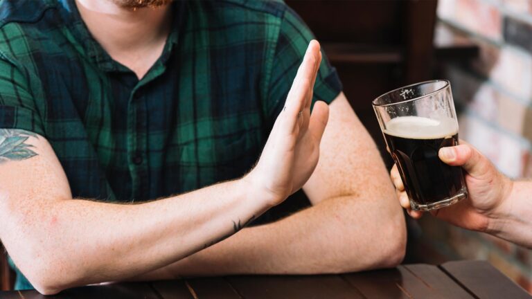 man refusing glass rum offered by his friend
