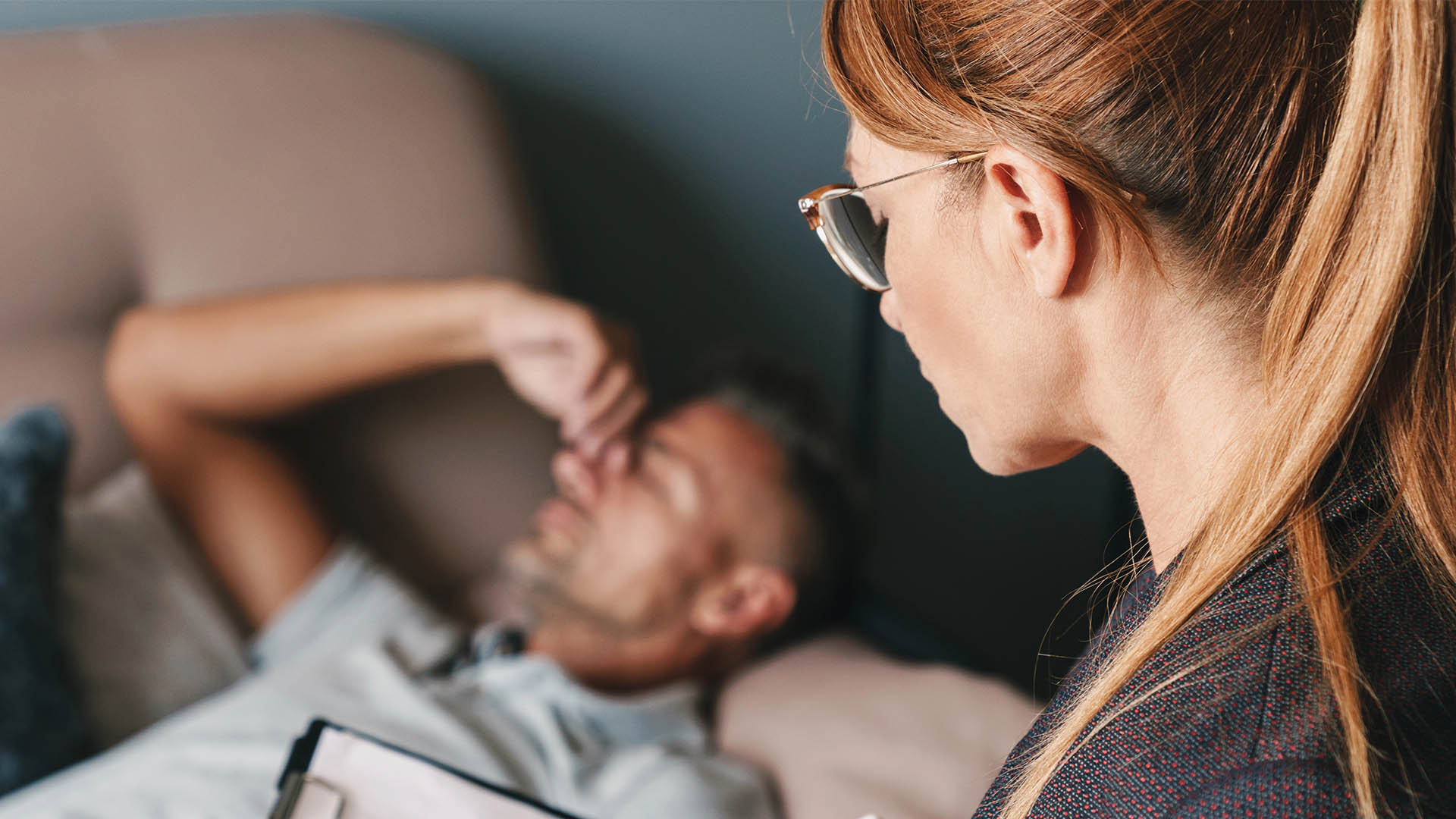 man lying on sofa and having conversation with psychologist