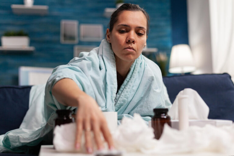 Woman in blanket experiencing nausea during detox and recovery.