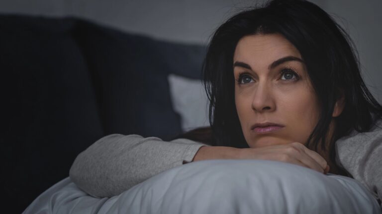 dissatisfied woman having insomnia while lying on bed at night