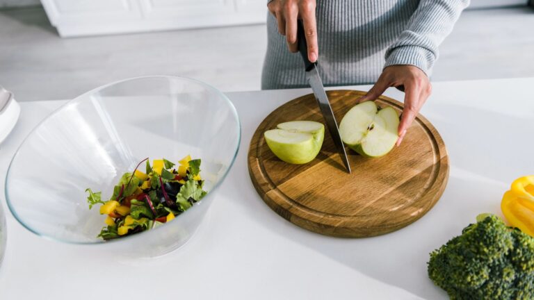 woman holding knife near halves of apple