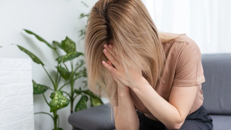 Sad tired young woman touching forehead