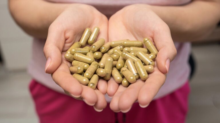Handful of green kratom pills in woman hands