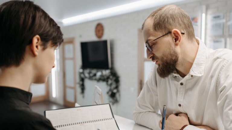 A receptionist and client converse over an appointment book