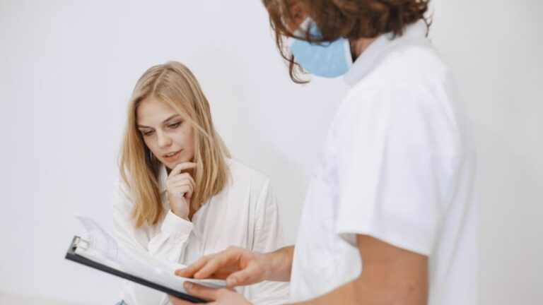 A doctor in a face mask discusses diagnosis with a patient