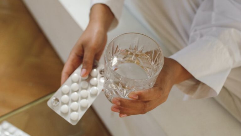 hands holding pills and a glass of water