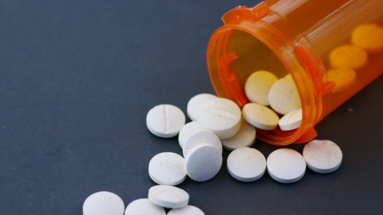 white pills scattered from an orange prescription bottle